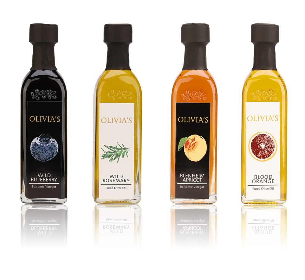 Product photo on white background with shadow of 4 yellow, black and orange olive oil and balsamic vinegar bottles