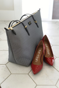 Mini Lifestyle photo of calvin klein red high heel shoes with striped bag on white tile floor by door