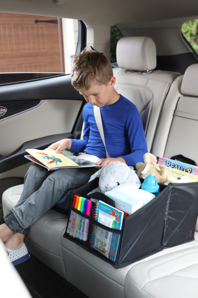 Lifestyle photo of boy in blue shirt reading a book in a car with toy box product
