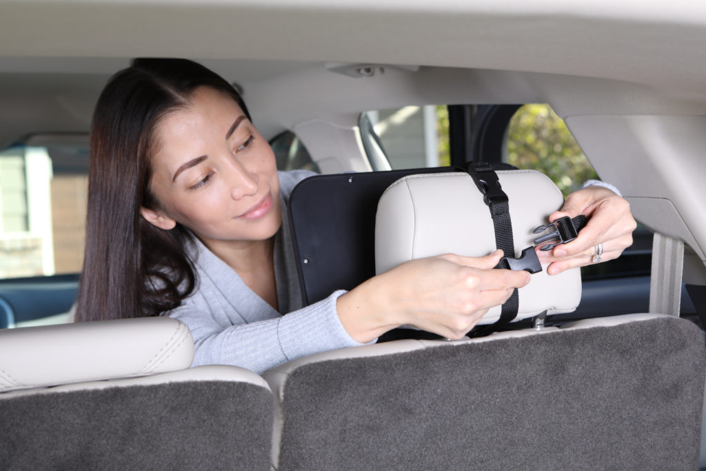 Lifestyle photo of woman in car demonstrating buckle of baby car product