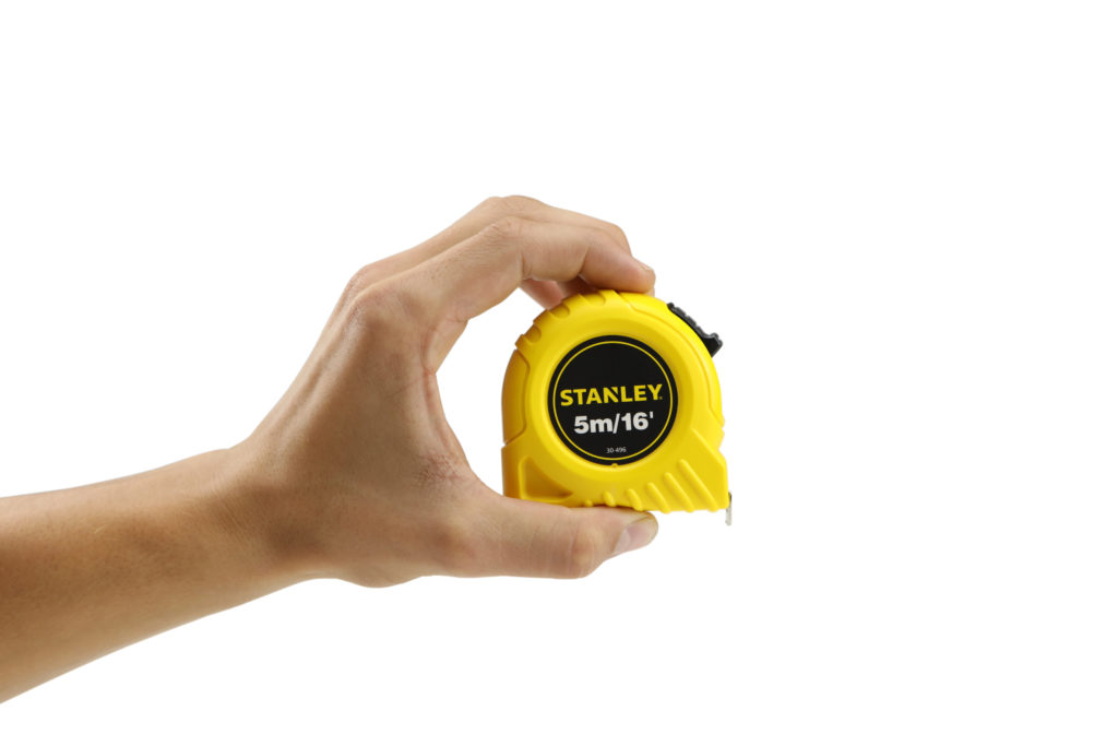 Hand model product photo on white background of hand holding a yellow stanley measuring tape