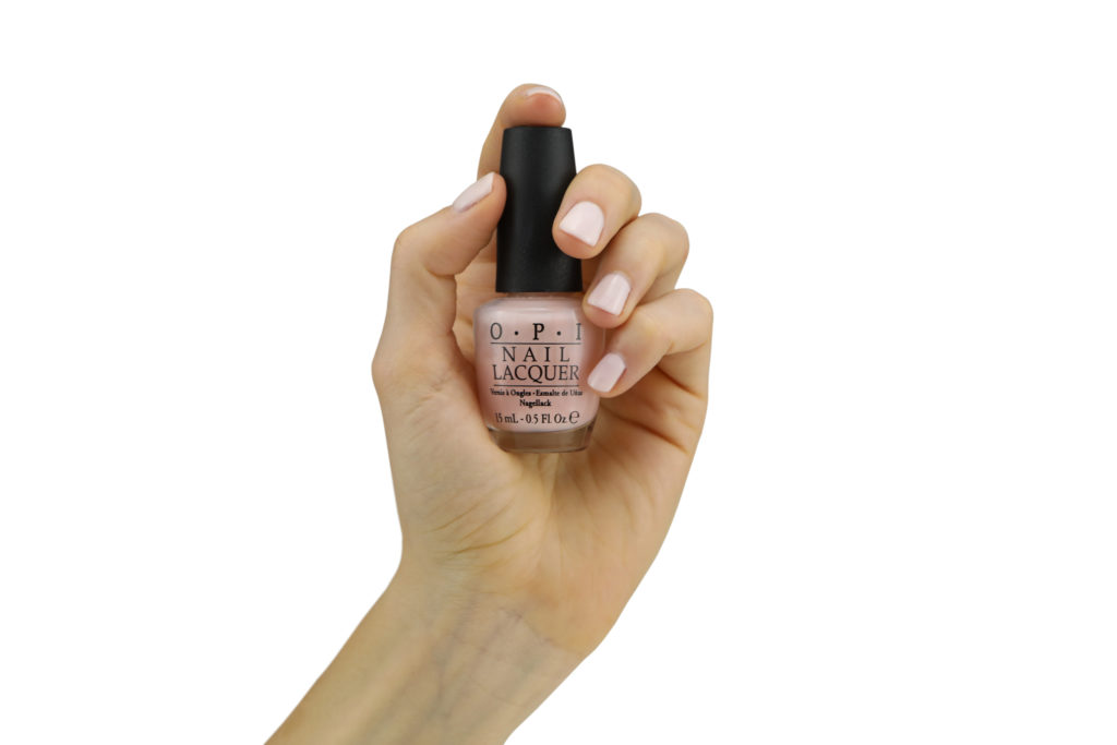 Hand model product photo on white background of hand holding pink nail polish