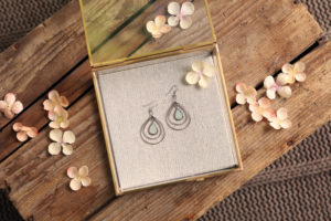 mini lifestyle photo of jewelry in box with peach flowers on wooden tabletop product photograph