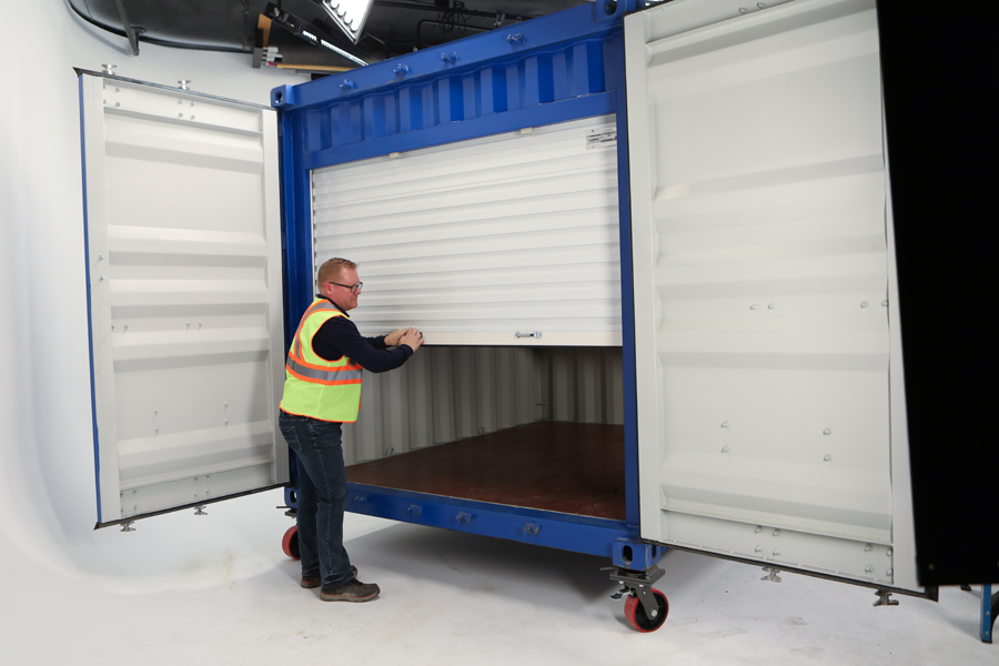 Lifestyle photo of man in yellow vest closing roller door of a blue steel box