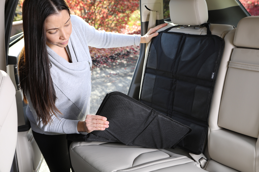 Product photo of woman wearing grey demonstrating baby car seat mat