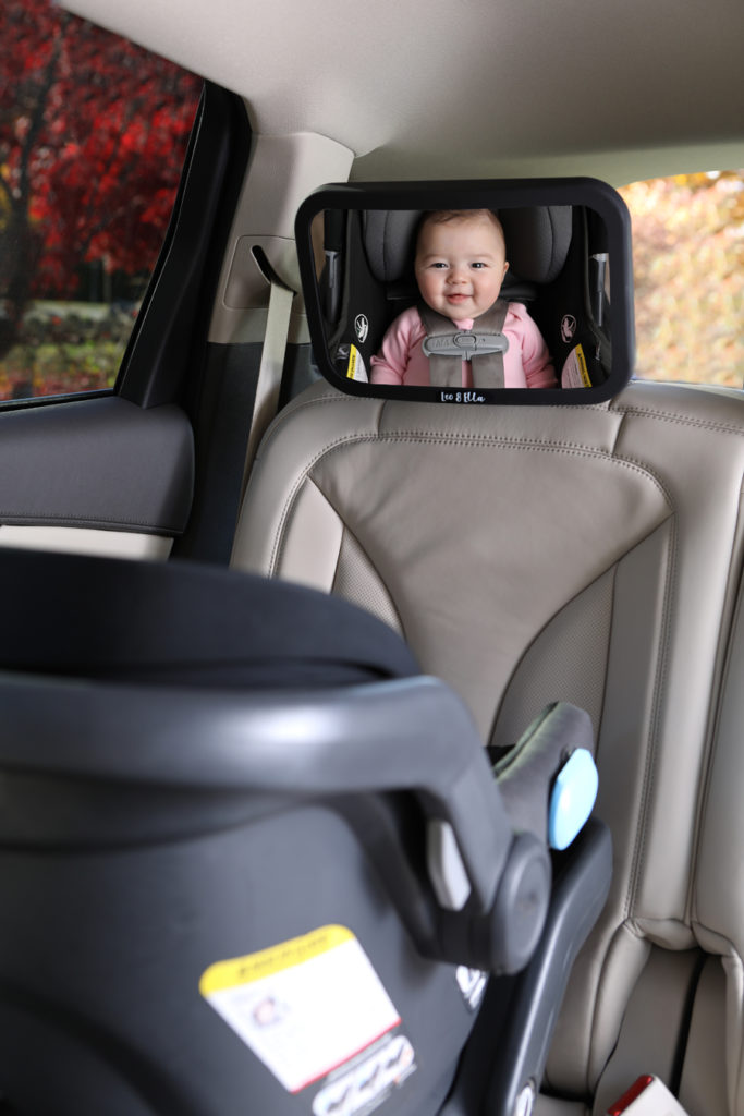 Lifestyle photo inside a car with a baby's face in a car mirror