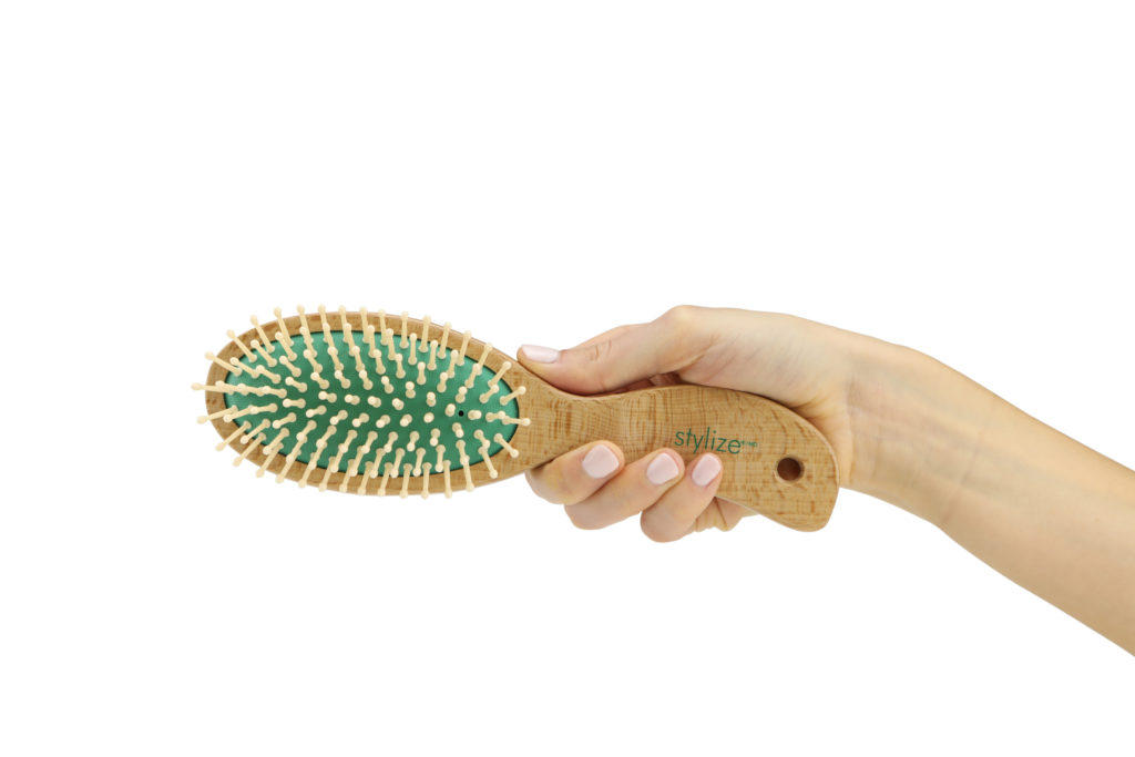 Hand model product photo on white background of hand holding a green hair brush