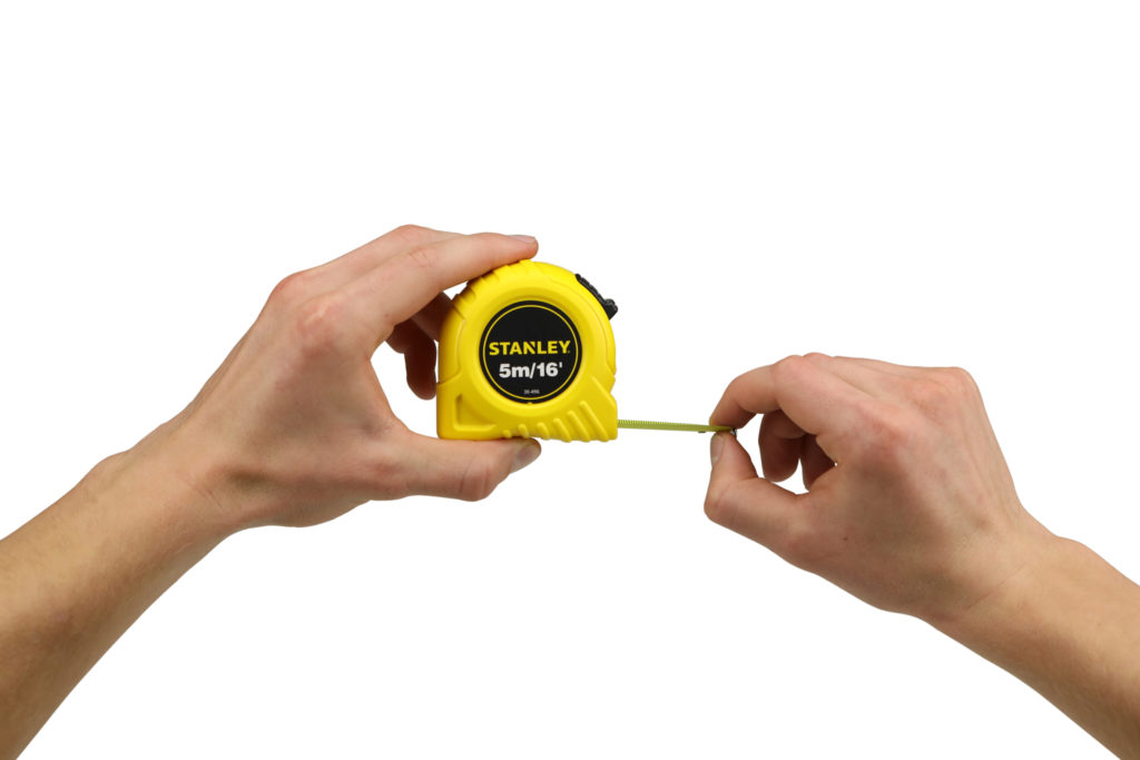 Hand model product photo on white background of hand holding a yellow stanley tape measure demonstrating