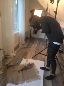 behind the scenes photo of taking a picture of a lifestyle set up of cream and burlap in front of window