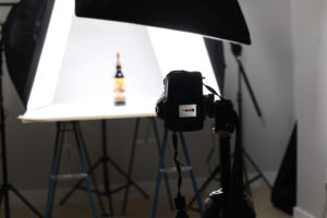 behind the camera photo of product photography of white bottle with photography lights